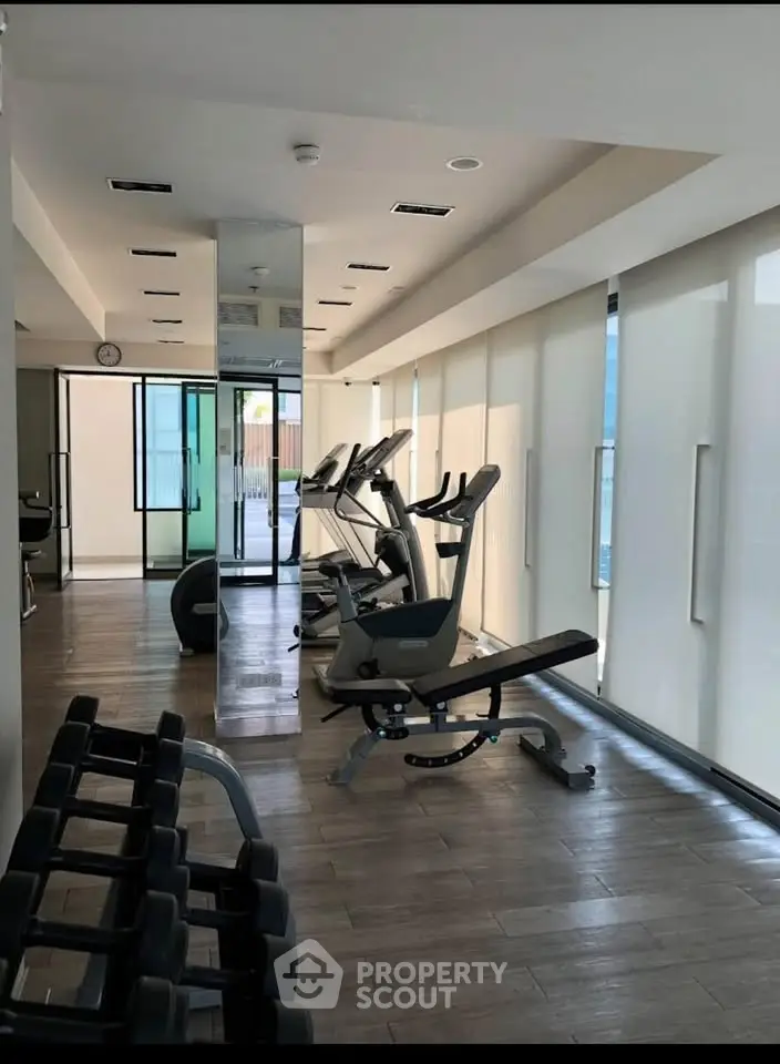 Modern gym with exercise equipment and large windows in a residential building.