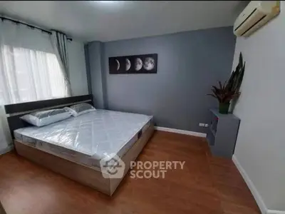 Modern bedroom with wooden flooring, stylish decor, and air conditioning unit.