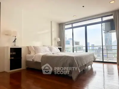 Spacious bedroom with city view and large windows in modern apartment