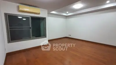 Spacious empty room with wooden flooring and air conditioning, ideal for customization.