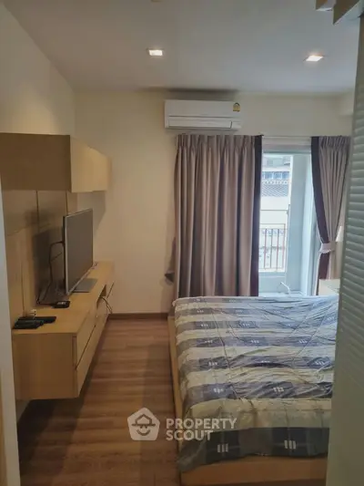 Cozy bedroom with modern furnishings and natural light from balcony window.