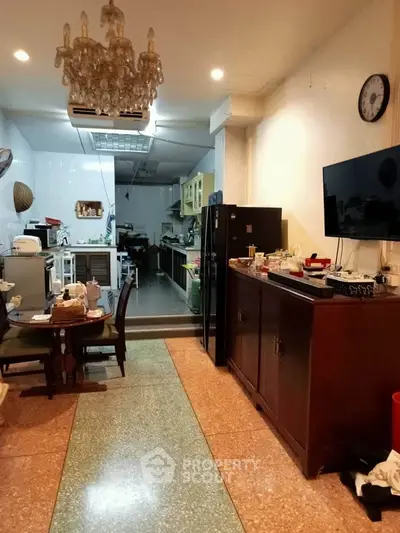 Spacious kitchen with open layout and modern appliances, featuring a dining area and elegant chandelier.