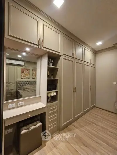 Elegant bedroom with built-in wardrobe and vanity in modern apartment