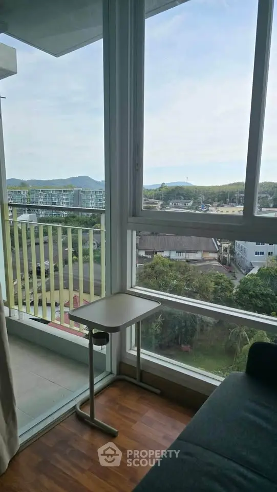 Bright corner unit with stunning view from high-rise balcony, featuring modern glass windows and cozy seating area.