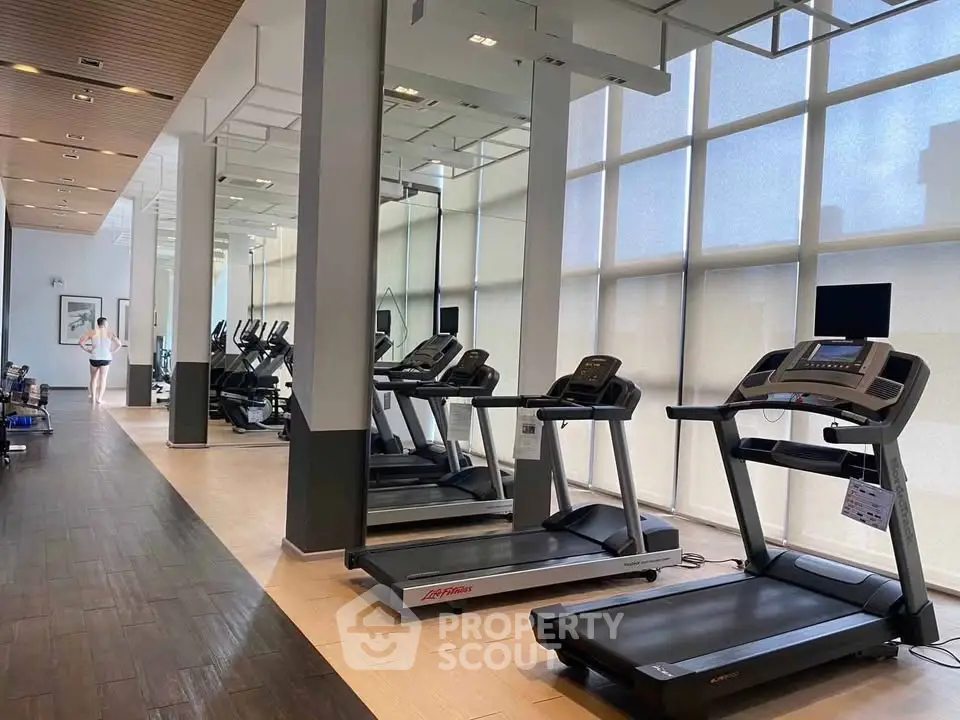 Modern gym with treadmills and large windows in luxury residential building.