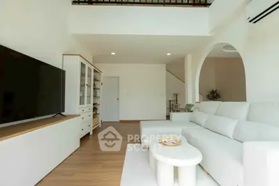 Spacious modern living room with white sofa and large TV, perfect for relaxation.