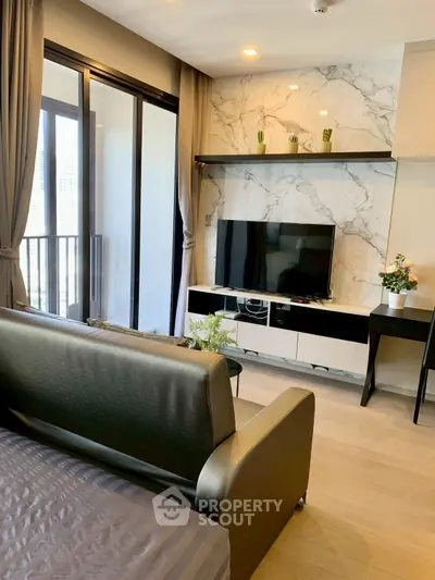 Modern living room with sleek design, large TV, and balcony access in a stylish apartment.