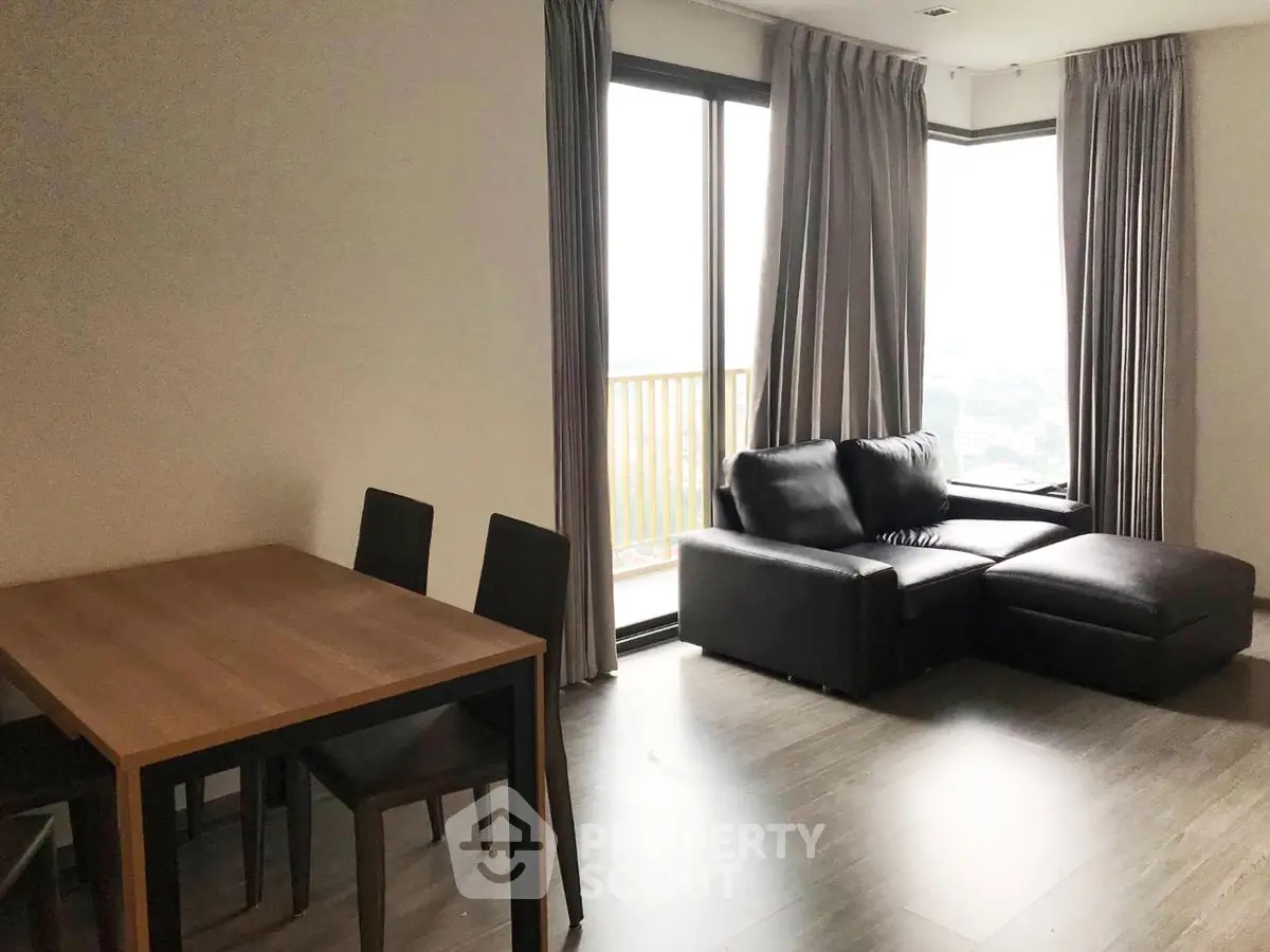 Modern living room with large windows and stylish furniture in a high-rise apartment.