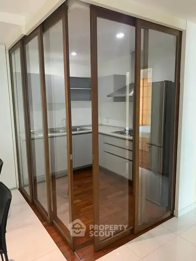 Modern kitchen with glass partition and sleek appliances in a compact layout.