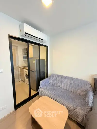 Modern living room with air conditioning and sliding glass doors leading to a compact kitchen.
