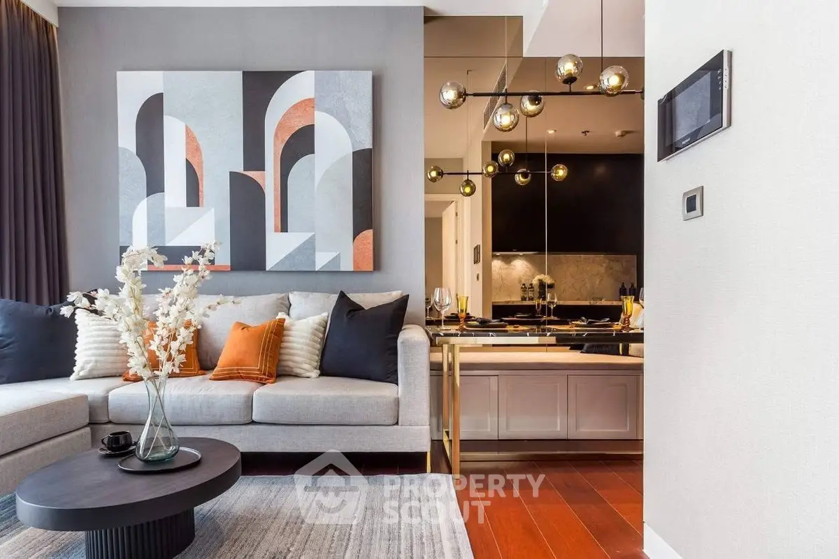 Modern living room with stylish decor and open kitchen layout, featuring elegant lighting and contemporary artwork.