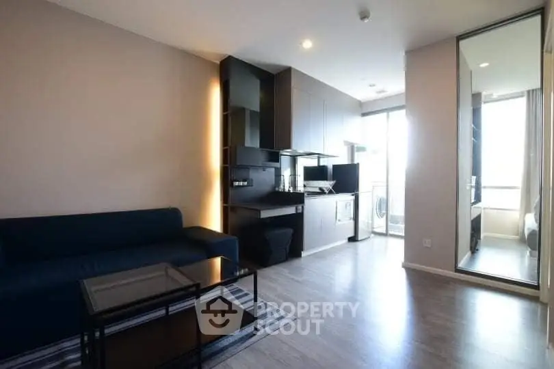 Modern living room with sleek kitchen and natural light, perfect for urban living.