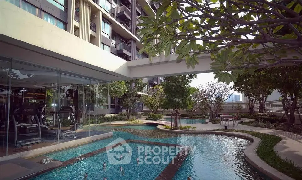 Luxurious apartment complex with modern gym and serene pool area surrounded by lush greenery.