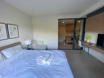 Modern bedroom with cozy decor and open layout leading to a stylish kitchen.