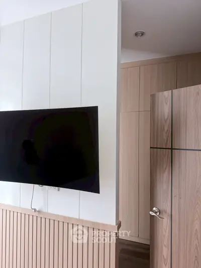 Modern interior with wall-mounted TV and sleek wooden cabinetry in a stylish living space.