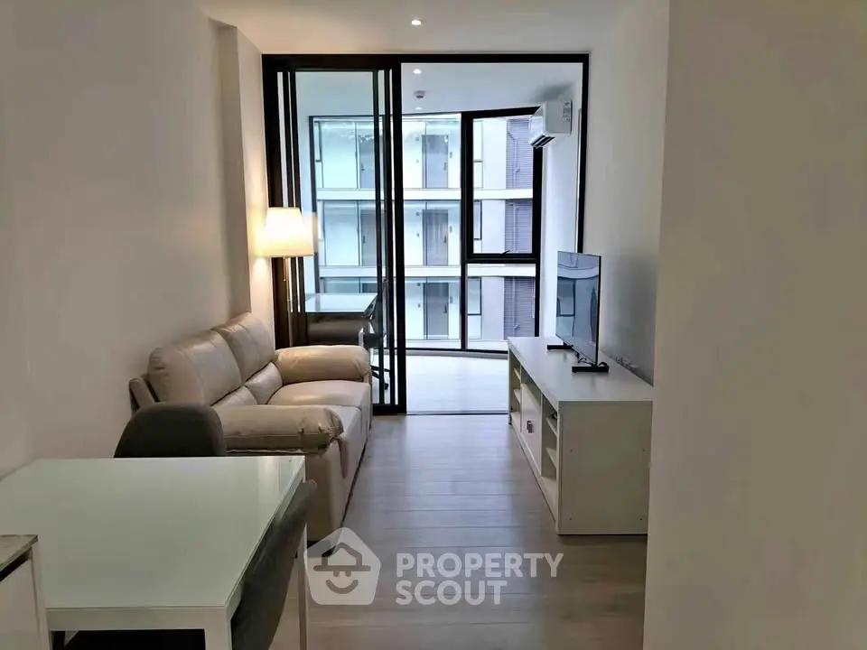Modern living room with sleek furniture and large windows offering natural light in a contemporary apartment.