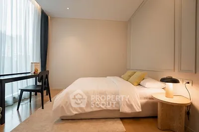 Modern bedroom with cozy lighting and elegant decor, featuring a comfortable bed and stylish desk by the window.