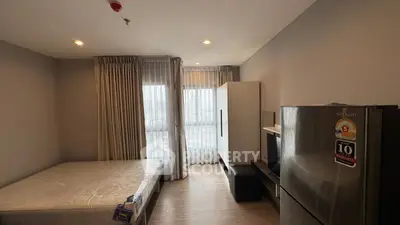 Modern bedroom with large window, stylish furniture, and sleek appliances in a cozy apartment.