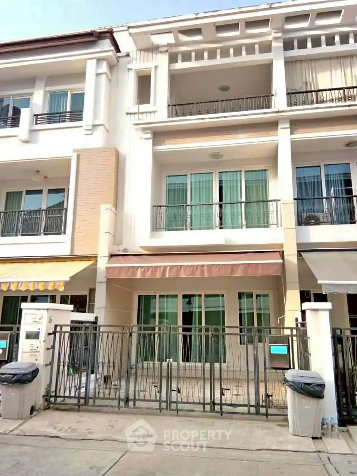 Charming three-story townhouse with balconies and gated entrance in a serene neighborhood.