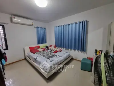 Cozy bedroom with modern decor and air conditioning, featuring blue curtains and a comfortable bed.