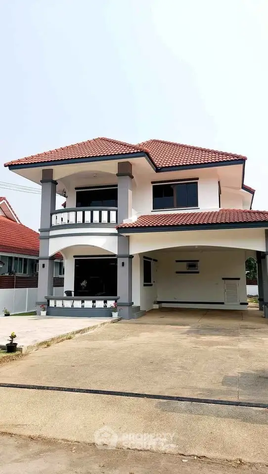 Charming two-story house with red-tiled roof and spacious driveway in a serene neighborhood.