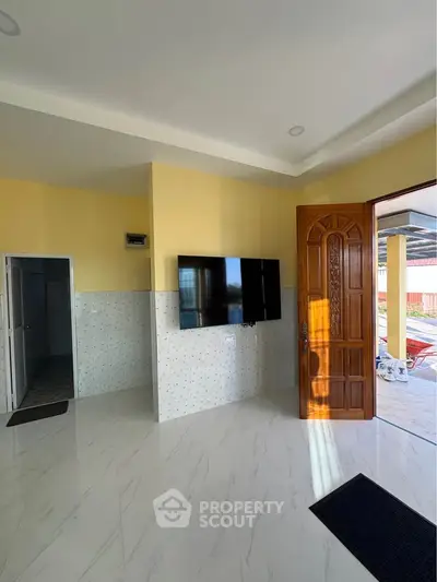 Modern living room with wall-mounted TV and open wooden door leading outside.