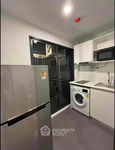 Modern kitchen with sleek appliances and washing machine in compact layout.
