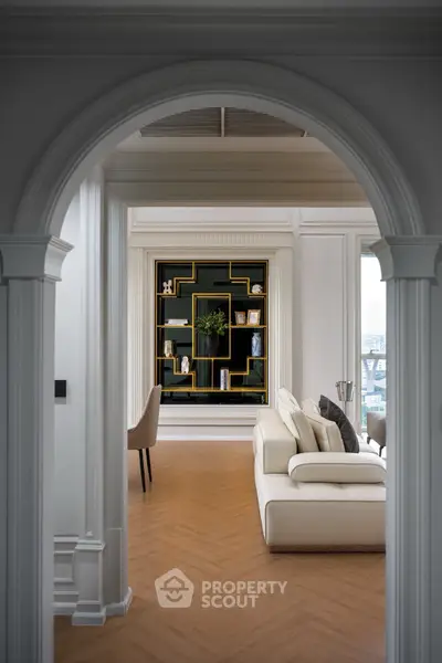 Elegant living room with archway, modern sofa, and stylish bookshelf.