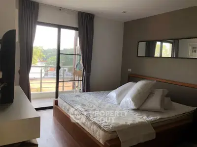 Spacious bedroom with balcony and scenic view, featuring modern decor and natural light.