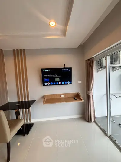 Modern living room with wall-mounted TV and sliding glass door to balcony.