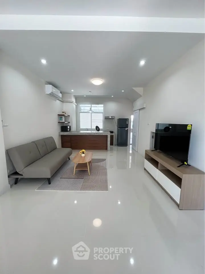 Modern open-plan living room with sleek furniture and integrated kitchen area.
