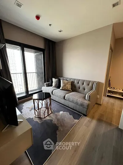 Modern living room with stylish sofa and balcony view in high-rise apartment.
