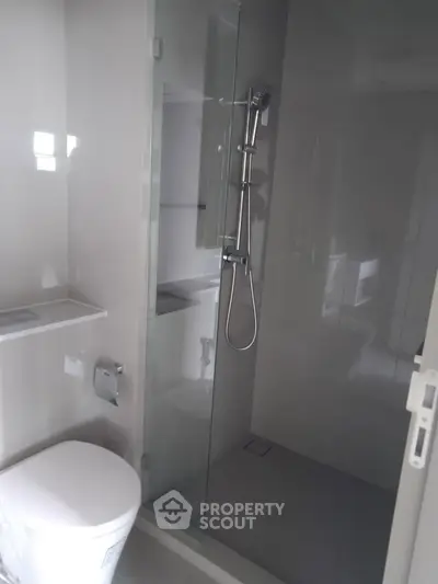 Modern bathroom with sleek shower and toilet in contemporary apartment.