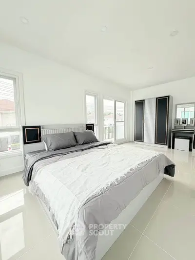 Spacious modern bedroom with large windows and sleek furnishings, offering abundant natural light and a serene atmosphere.