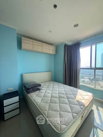 Bright bedroom with large window offering stunning city views, featuring a comfortable bed and modern decor.