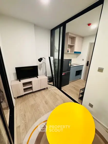 Modern compact living room with stylish furniture and open kitchen layout.