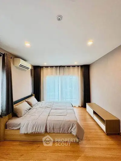 Spacious modern bedroom with large window and elegant wooden flooring