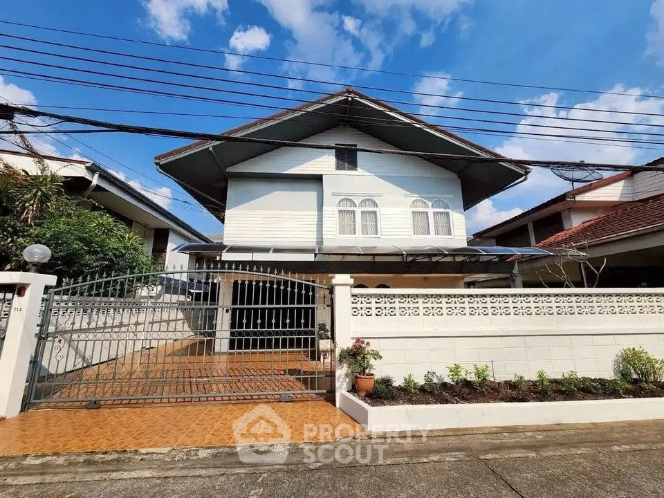 Charming two-story house with gated entrance and tiled driveway in a serene neighborhood.