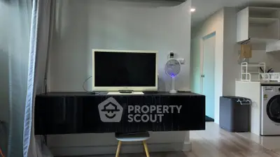 Modern living room with sleek black TV stand, wall-mounted TV, and compact washing machine in corner.