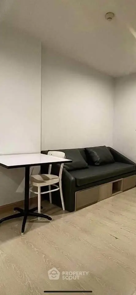 Modern minimalist living room with sleek black sofa and white table, perfect for urban living.