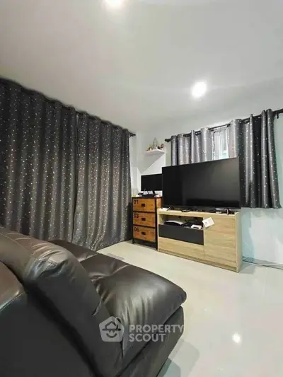 Modern living room with sleek leather sofa and large TV, perfect for entertainment.