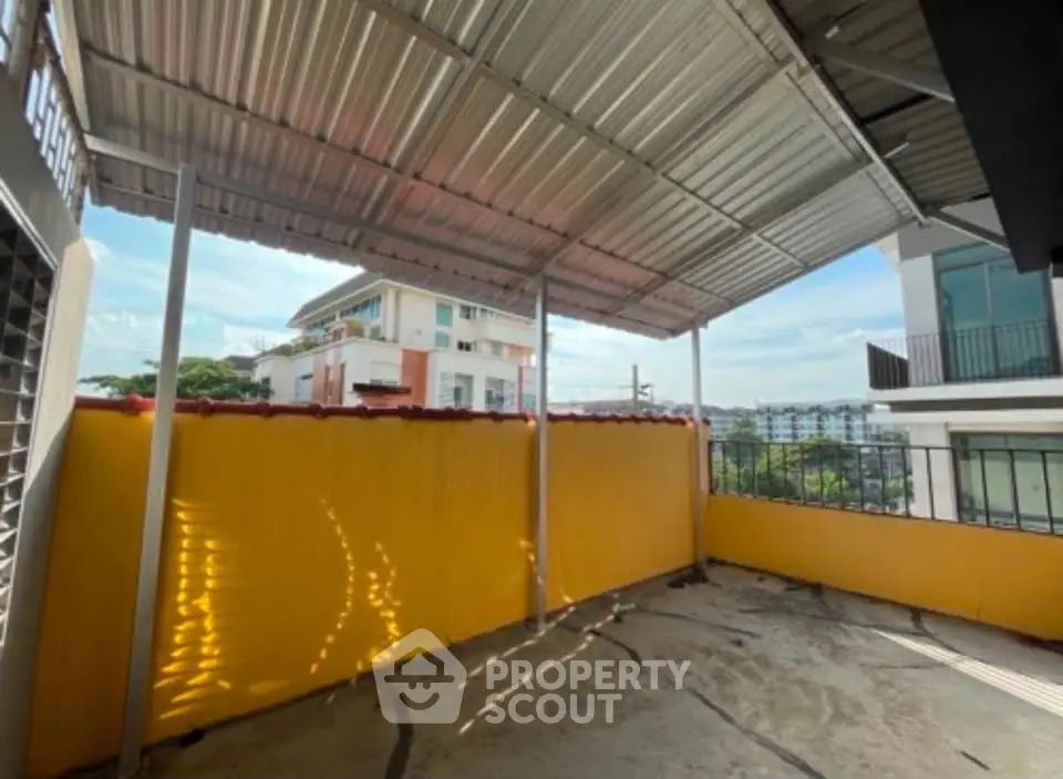Spacious covered balcony with urban view, perfect for relaxation and outdoor activities.