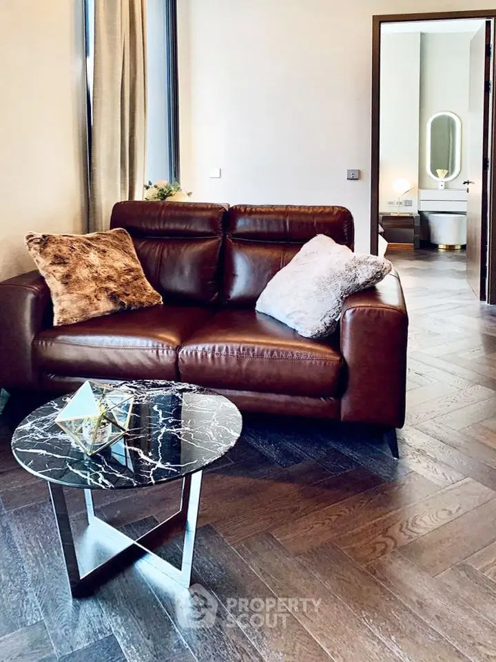 Stylish living room with leather sofa and modern decor, leading to a chic bathroom.