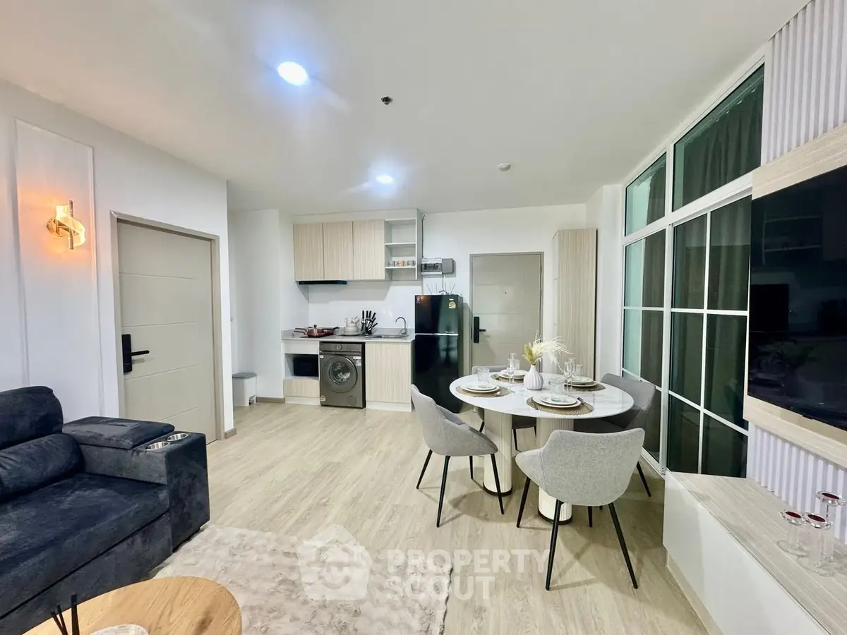 Modern open-plan living room with kitchen, featuring sleek furniture and appliances.