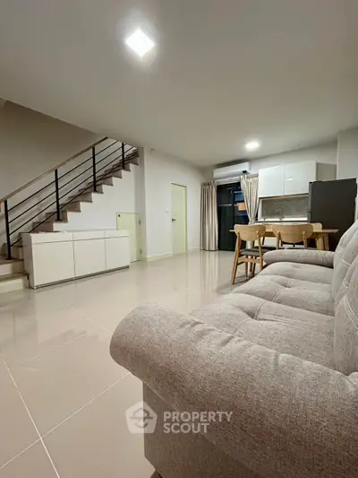 Spacious modern living room with sleek staircase and open kitchen layout