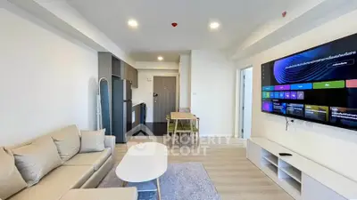 Modern living room with open kitchen, stylish furniture, and wall-mounted TV in a contemporary apartment.