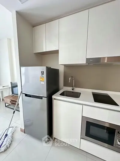 Modern kitchen with sleek cabinets, stainless steel fridge, and built-in appliances in a stylish apartment.
