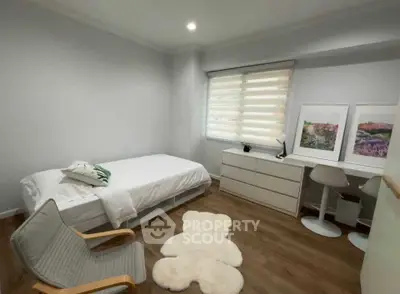 Cozy bedroom with modern decor, featuring a single bed, stylish chair, and elegant artwork.