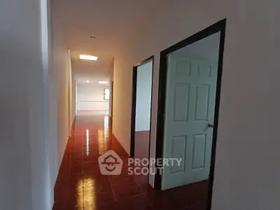Spacious hallway with glossy tiled flooring and open doors leading to bright rooms.