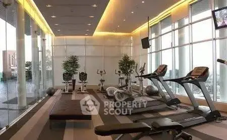 Luxurious gym with modern equipment and floor-to-ceiling windows in upscale residential building.